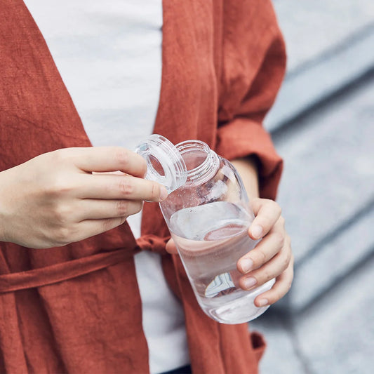 Person holding a clear water bottle with a blurred background