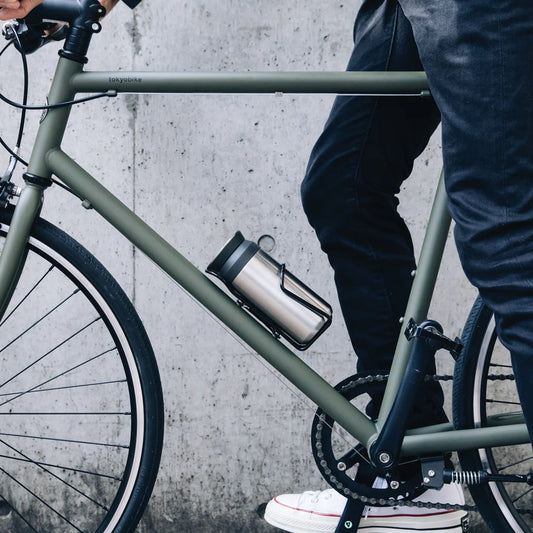 Person with a green bicycle against a concrete wall
