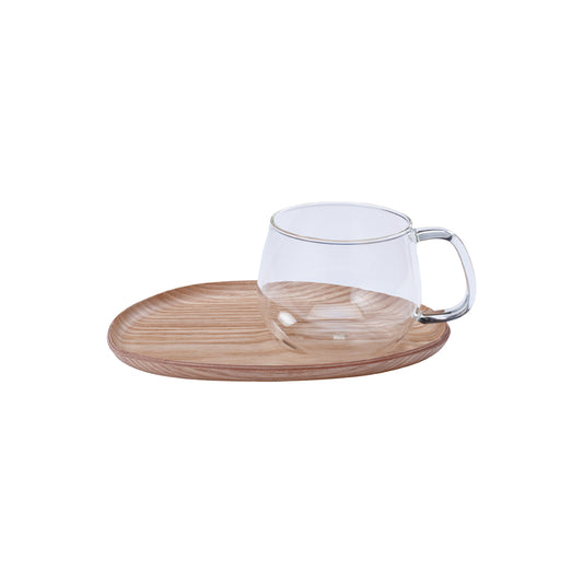 Clear glass mug with white interior on a wooden tray against a white background