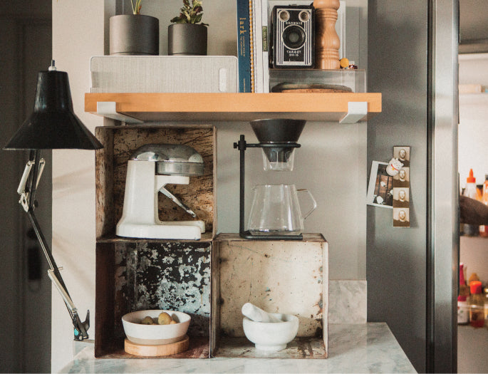 Small kitchen setup with wooden shelves, appliances, and decor.