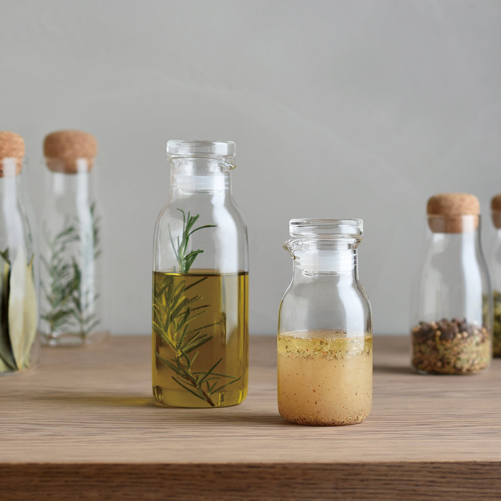 Glass bottles with liquid and herbs on a wooden surface