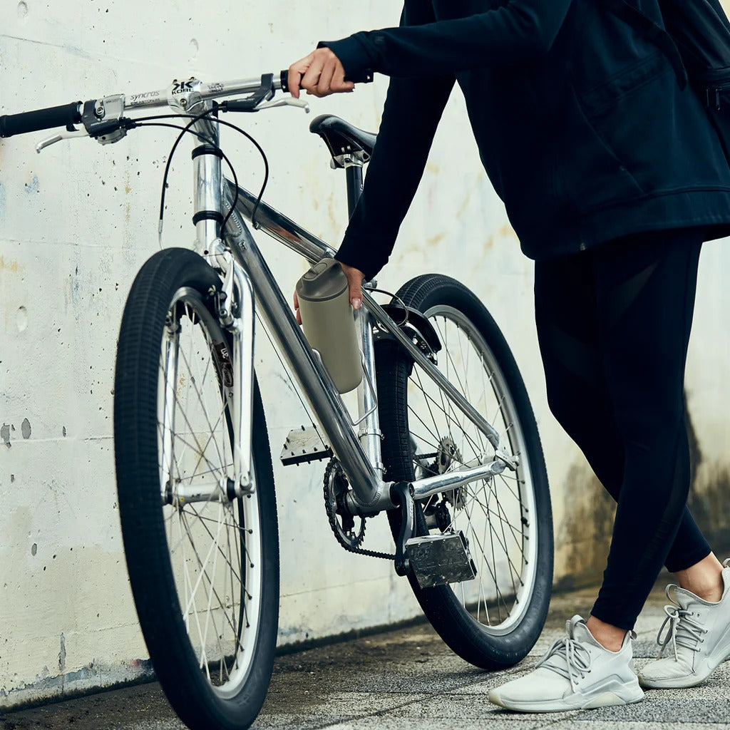 Person holding a bicycle against a textured wall.